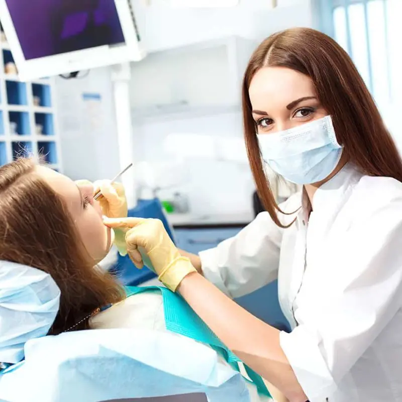 Klinikai fogászati higiénikus képzés visszanézhető órákkal és online jegyzetekkel a Pannon Kincstár iskolában. Barna hajú fogorvos kezeli a páciensét.