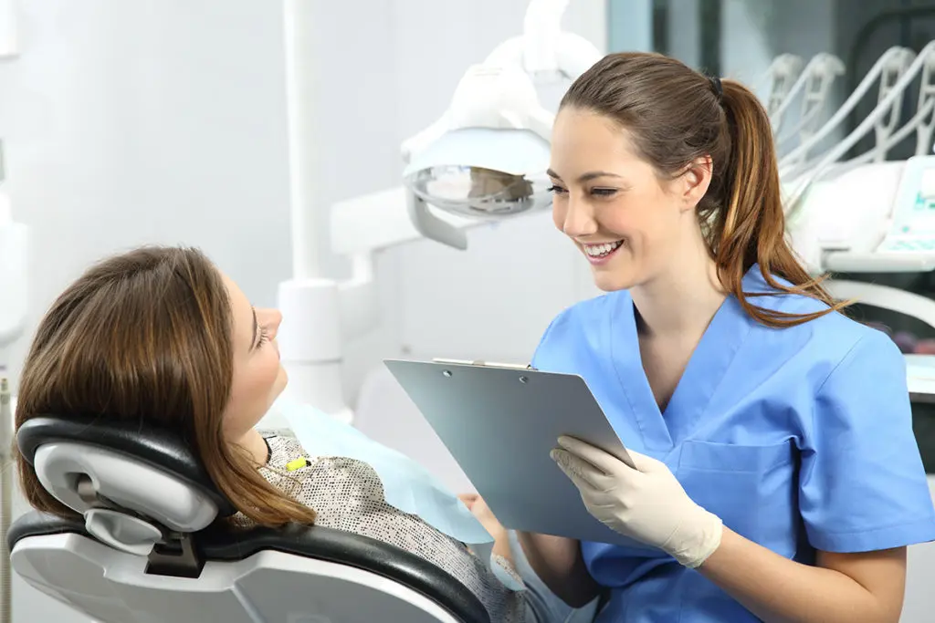 Boldog fogorvos hölgy beszélget páciensével a fogászaton. Pannon Kincstár