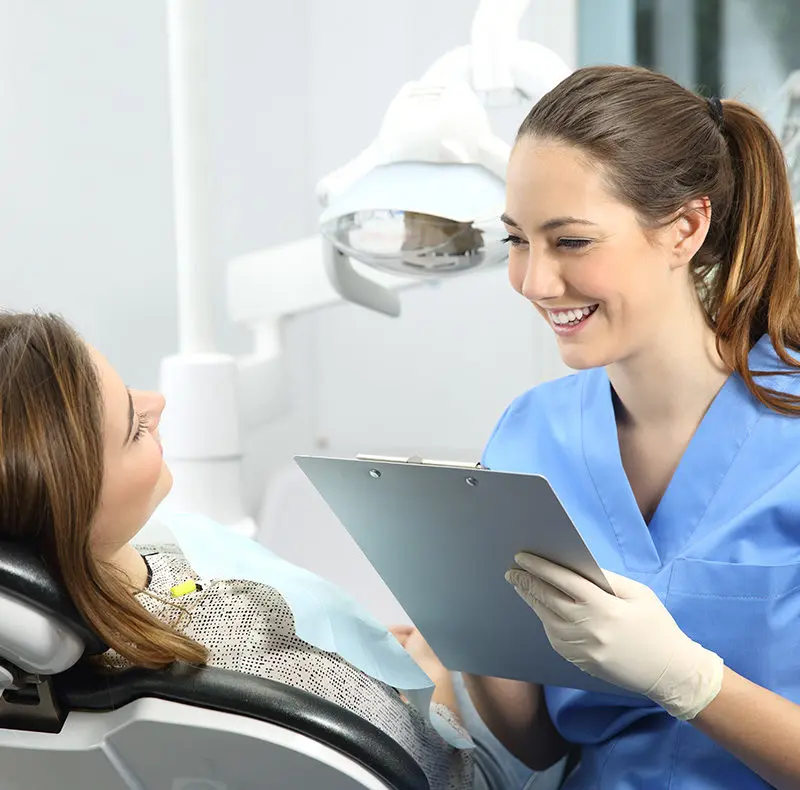 Boldog fogorvos hölgy beszélget páciensével a fogászaton. Pannon Kincstár