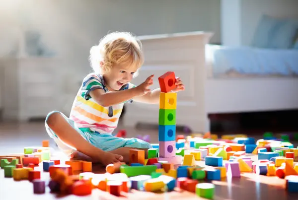 Vidám, szőke kisfiú játszik színes műanyag játékaival. Pannon Kincstár
