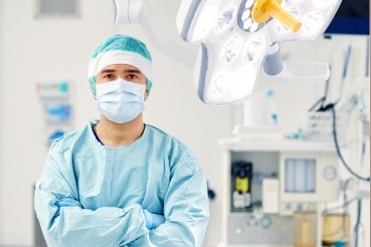 Egy műtőssegéd-gipszmester a műtőben áll kék orvosi ruhában.