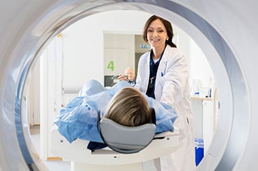 A szakasszisztens hölgy egy CT/MR gépbe helyezi be páciensét.