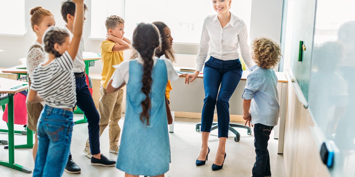 group of classmates standing around teacher at classroom and having fun