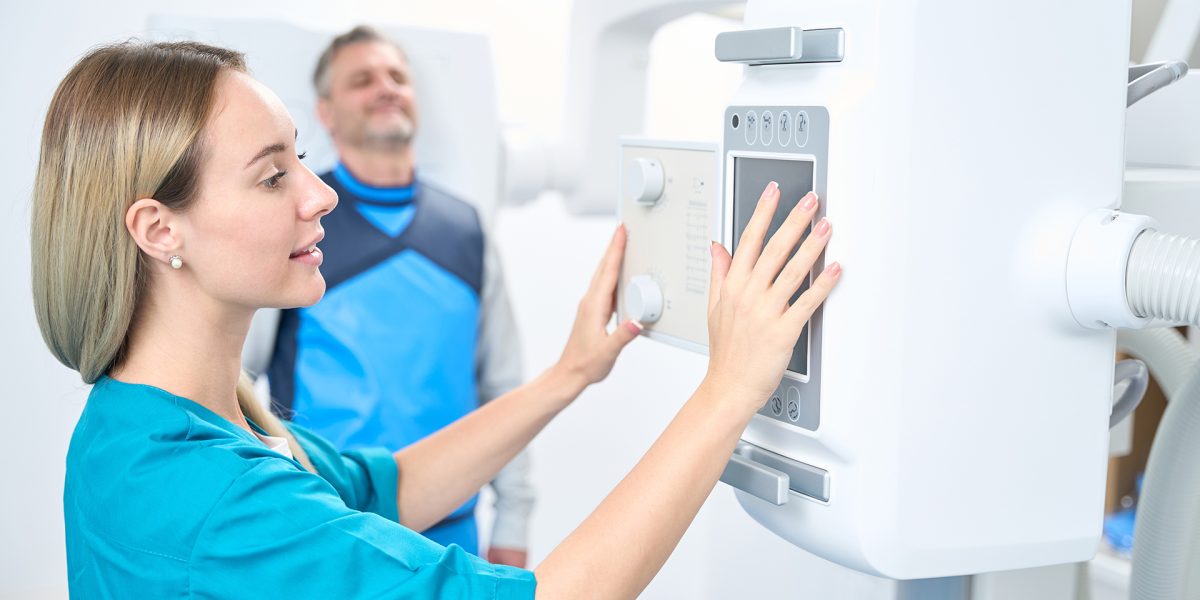 Caucasian woman turns on the x-ray machine while the patient is waiting