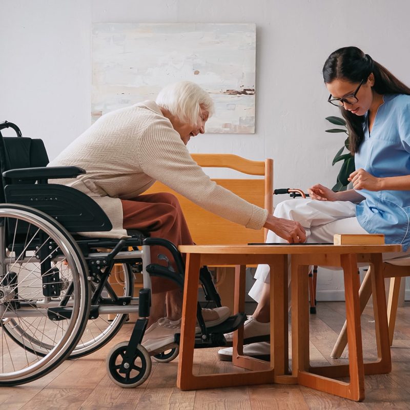 Hospise szakápoló nő egy kerekesszékben ülő, idős beteg hölgy társaságában. Hospise szakápoló képzés a Pannon Kincstárban