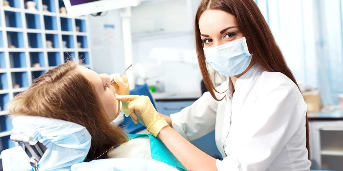 Klinikai fogászati higiénikus képzés visszanézhető órákkal és online jegyzetekkel a Pannon Kincstár iskolában. Barna hajú fogorvos kezeli a páciensét.